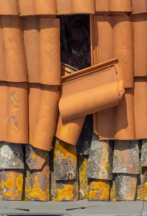 Detalhe aproximado de telhas cerâmicas de cumeaeira danificadas e fora do sítio, detetadas durante inspeção técnica aérea com drone